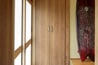  ドアから引き戸に交換し、格子の隙間から光が入る明るい玄関に。下駄箱は天井近くまでのサイズに造り変え。三和土（たたき）はタイルに変更し、京壁は塗り替えました。